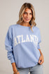 A woman wearing a light blue crewneck sweatshirt with &