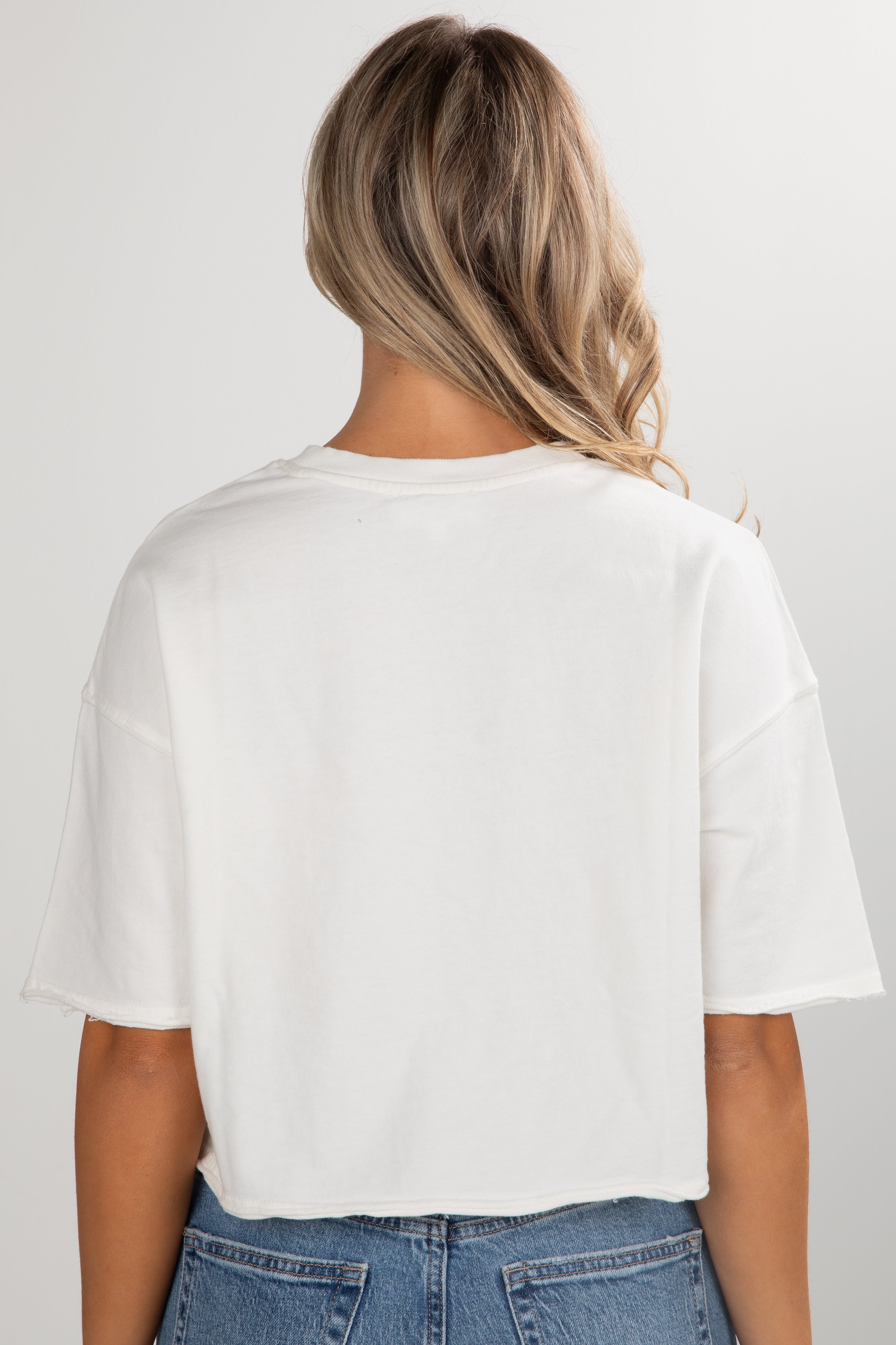 Person wearing a white t-shirt and blue jeans on a plain background