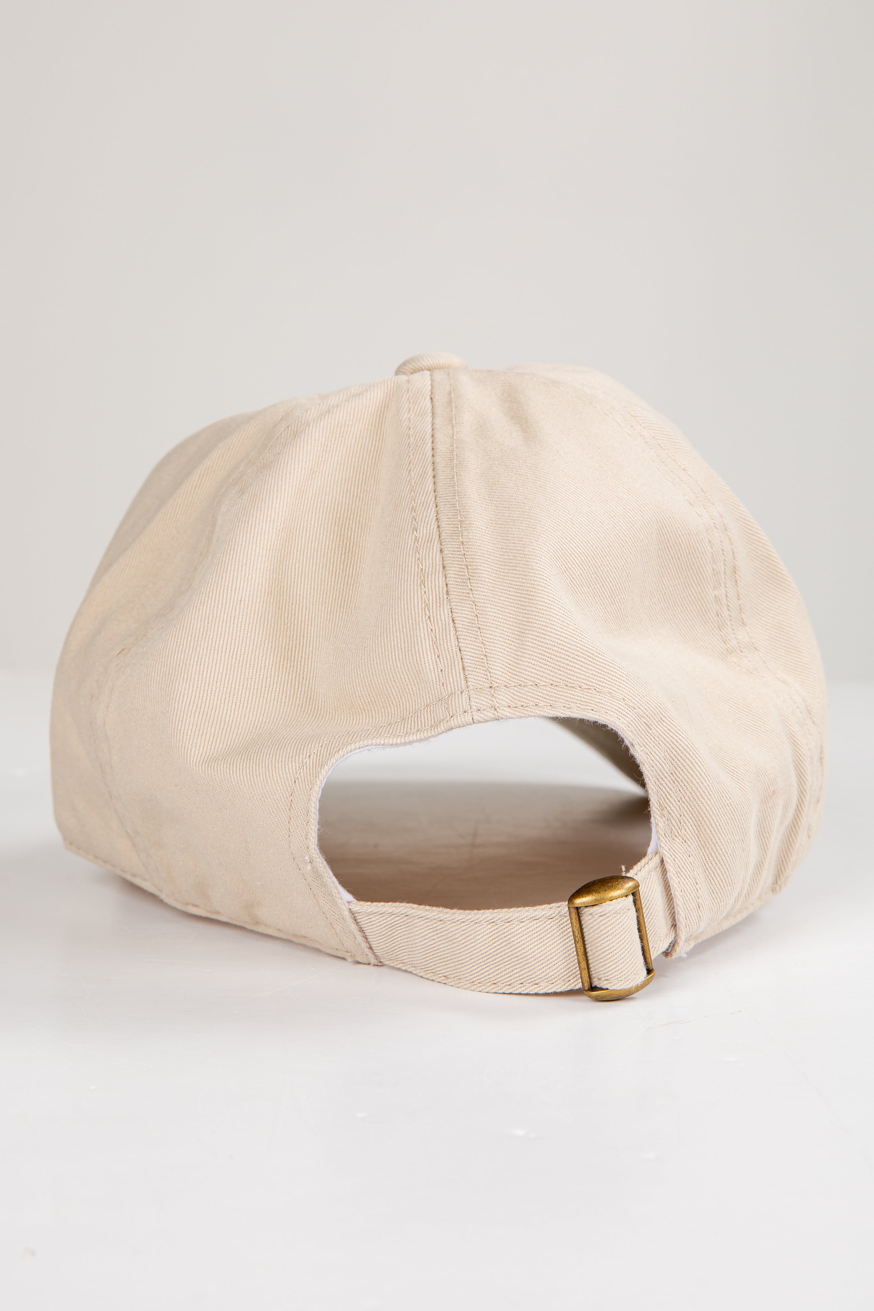 Beige baseball cap with a gold buckle on a light gray background