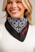A smiling blonde woman wearing a black bandana with a white paisley pattern and red embroidered script reading &