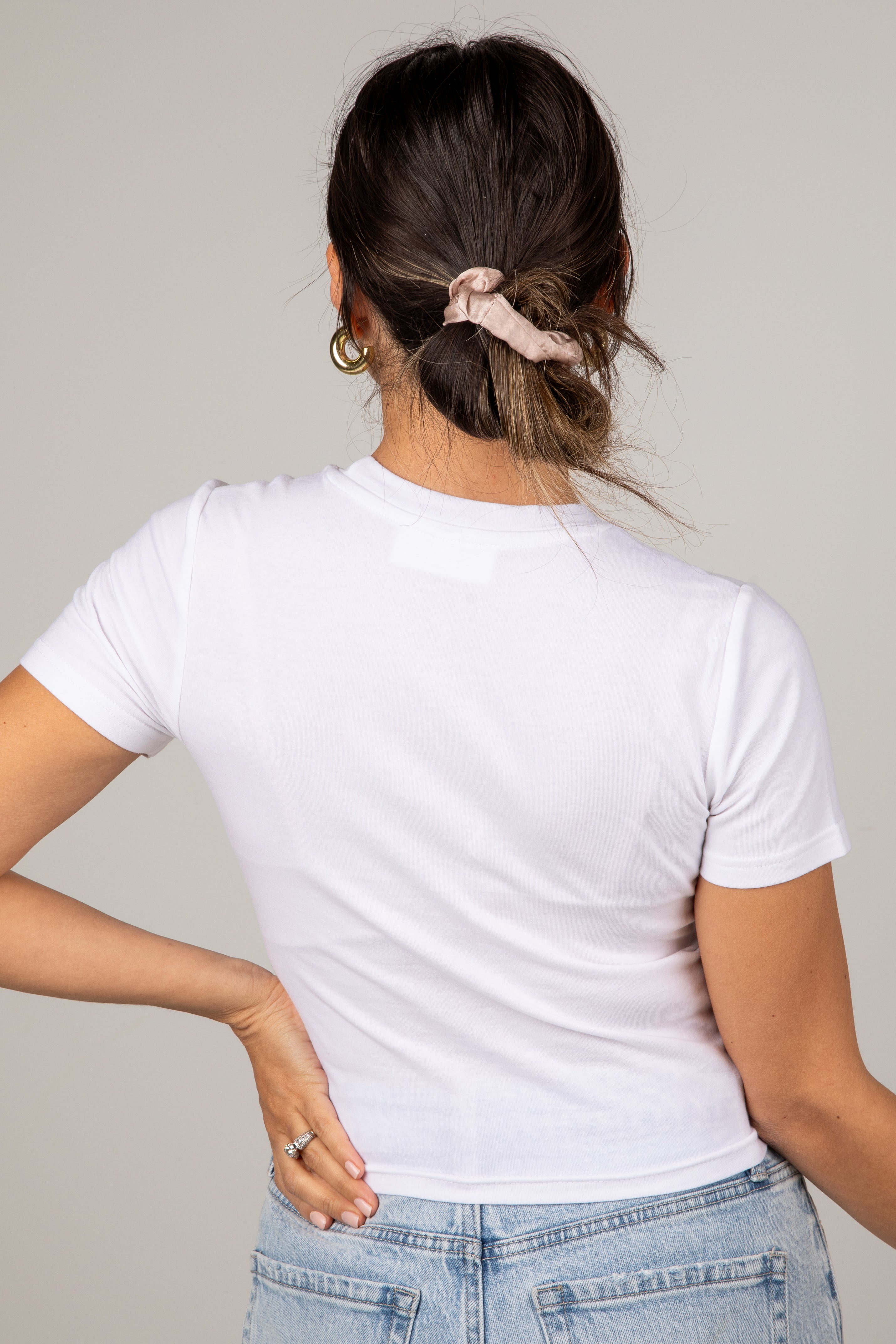Person wearing a white t-shirt and blue jeans with a neutral background