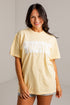 A woman wearing a pale yellow oversized t-shirt with &