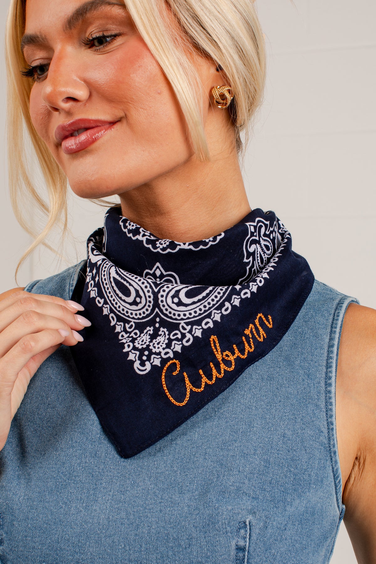 A close-up of a woman wearing a navy blue bandana with a white paisley pattern and the word &