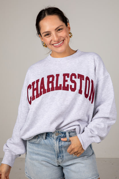 Woman wearing a gray sweatshirt with &