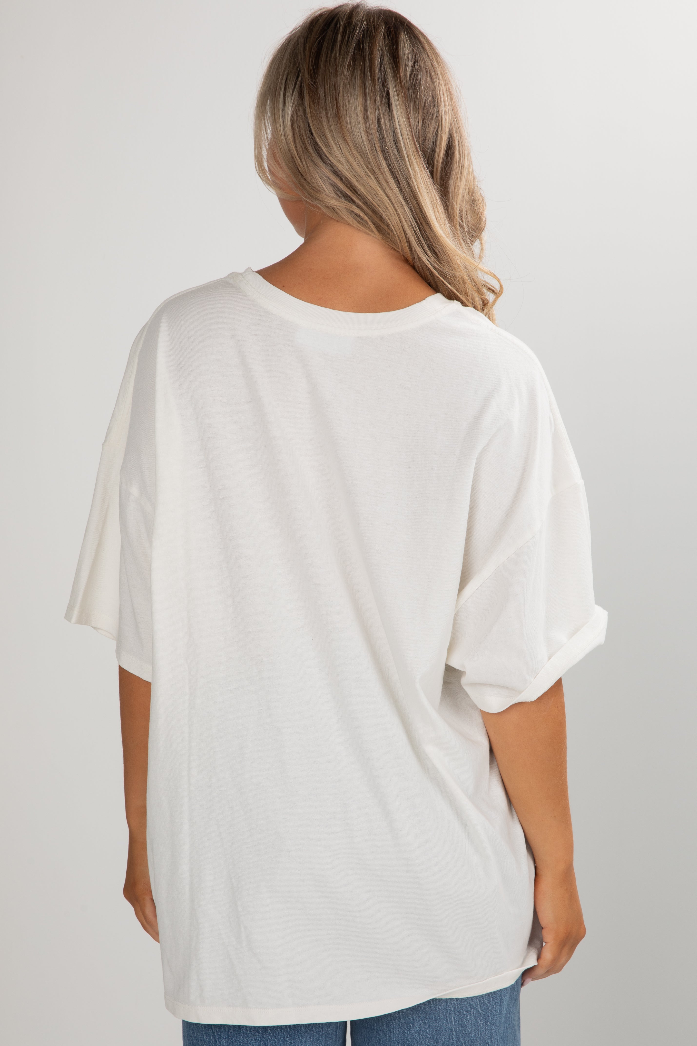 Person wearing a white oversized t-shirt on a plain background