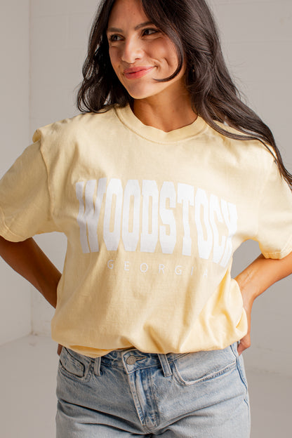 A woman wearing a pale yellow t-shirt with &