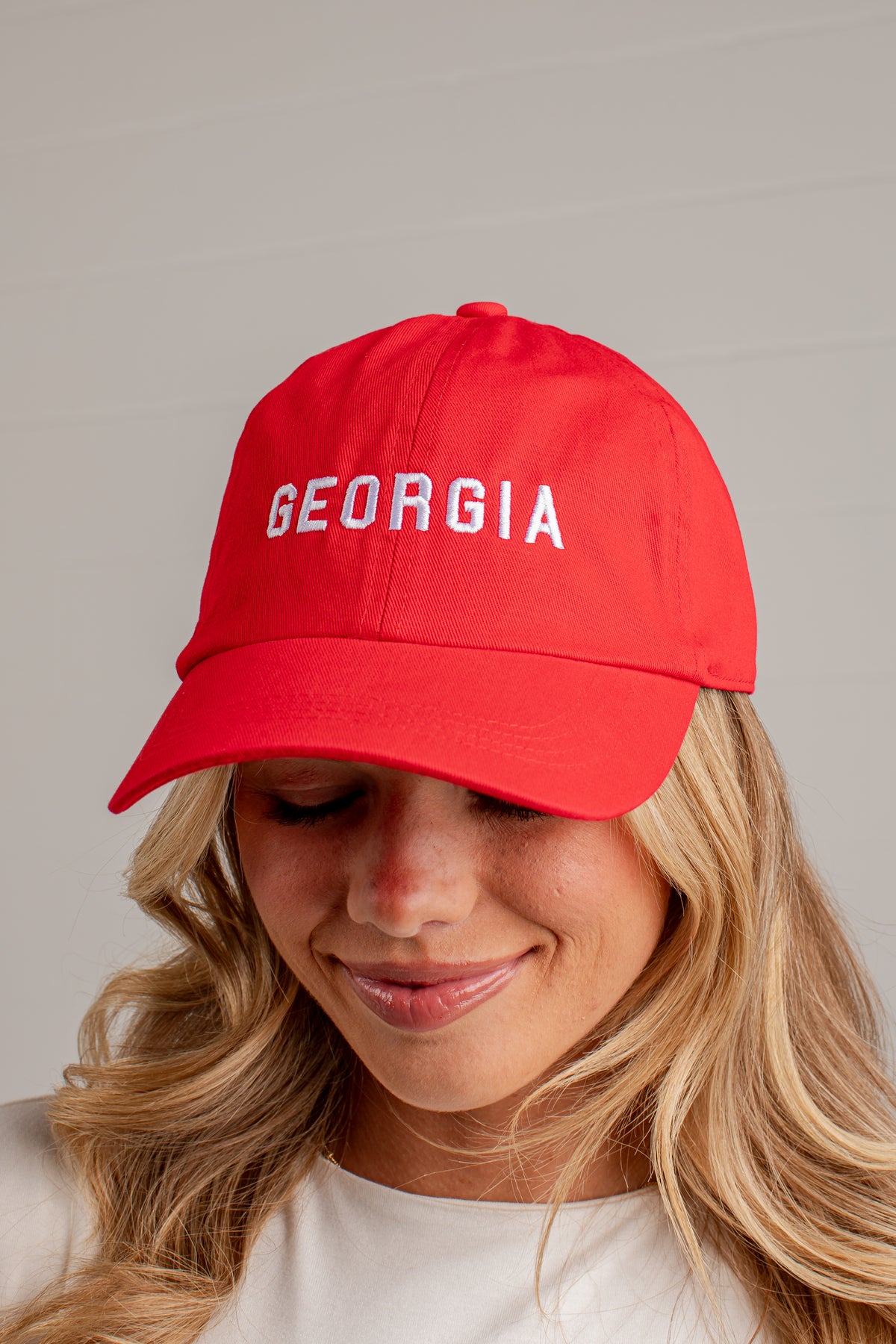 A woman wearing a bright red baseball cap with &