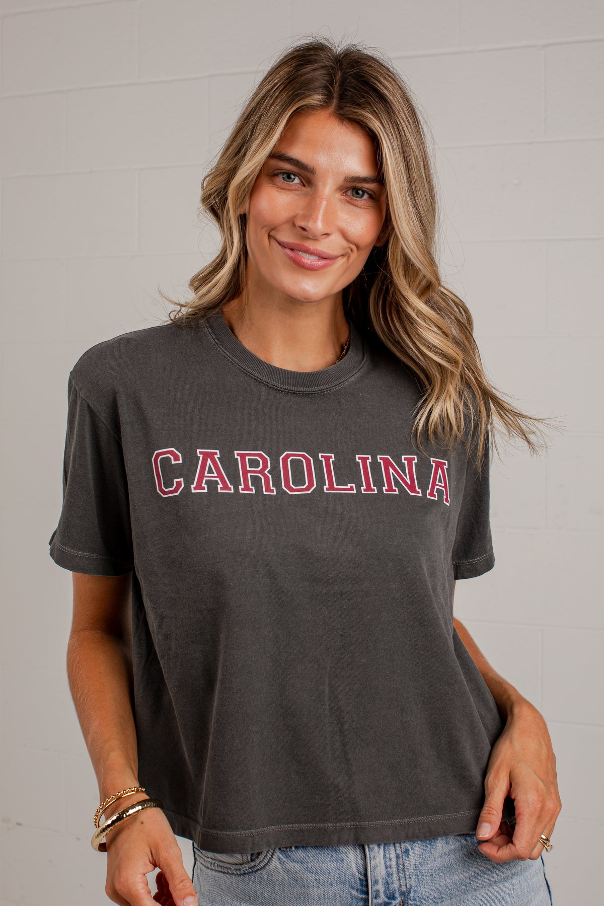 A woman wearing a dark charcoal gray short-sleeve t-shirt with &