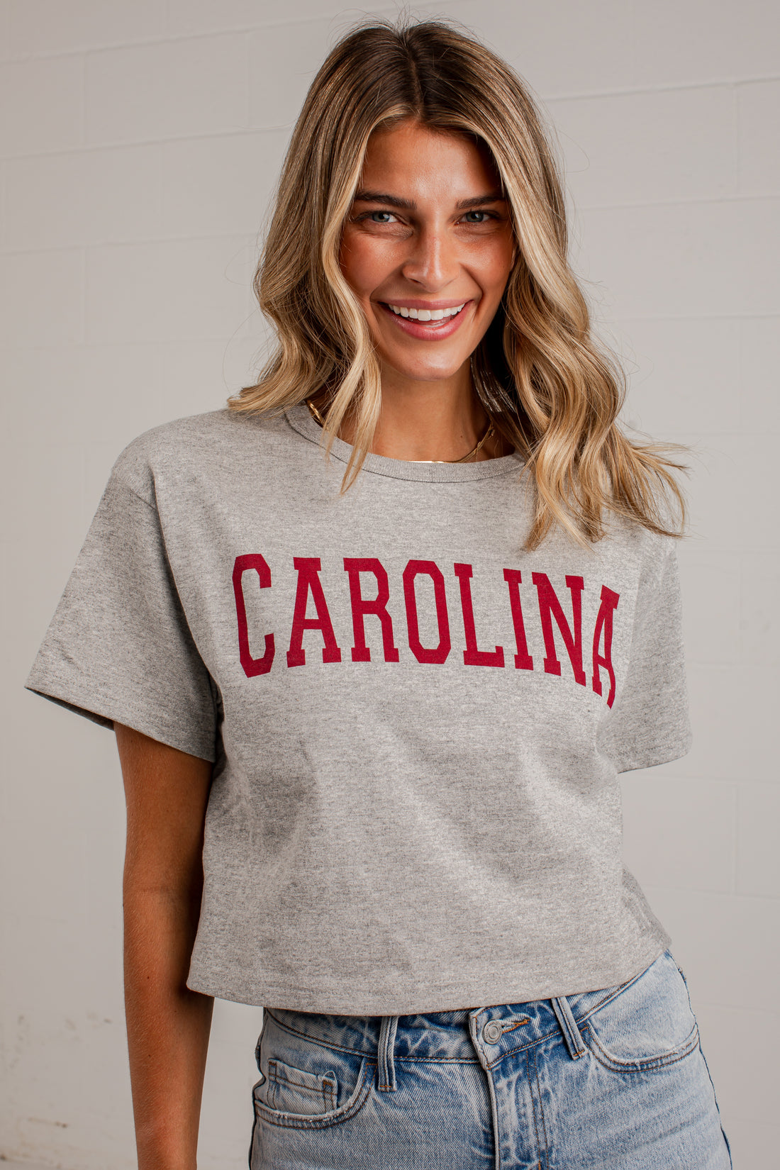 A woman wearing a heather gray cropped t-shirt with &
