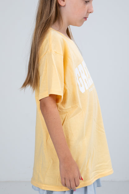 Child wearing a yellow t-shirt with text on a plain background
