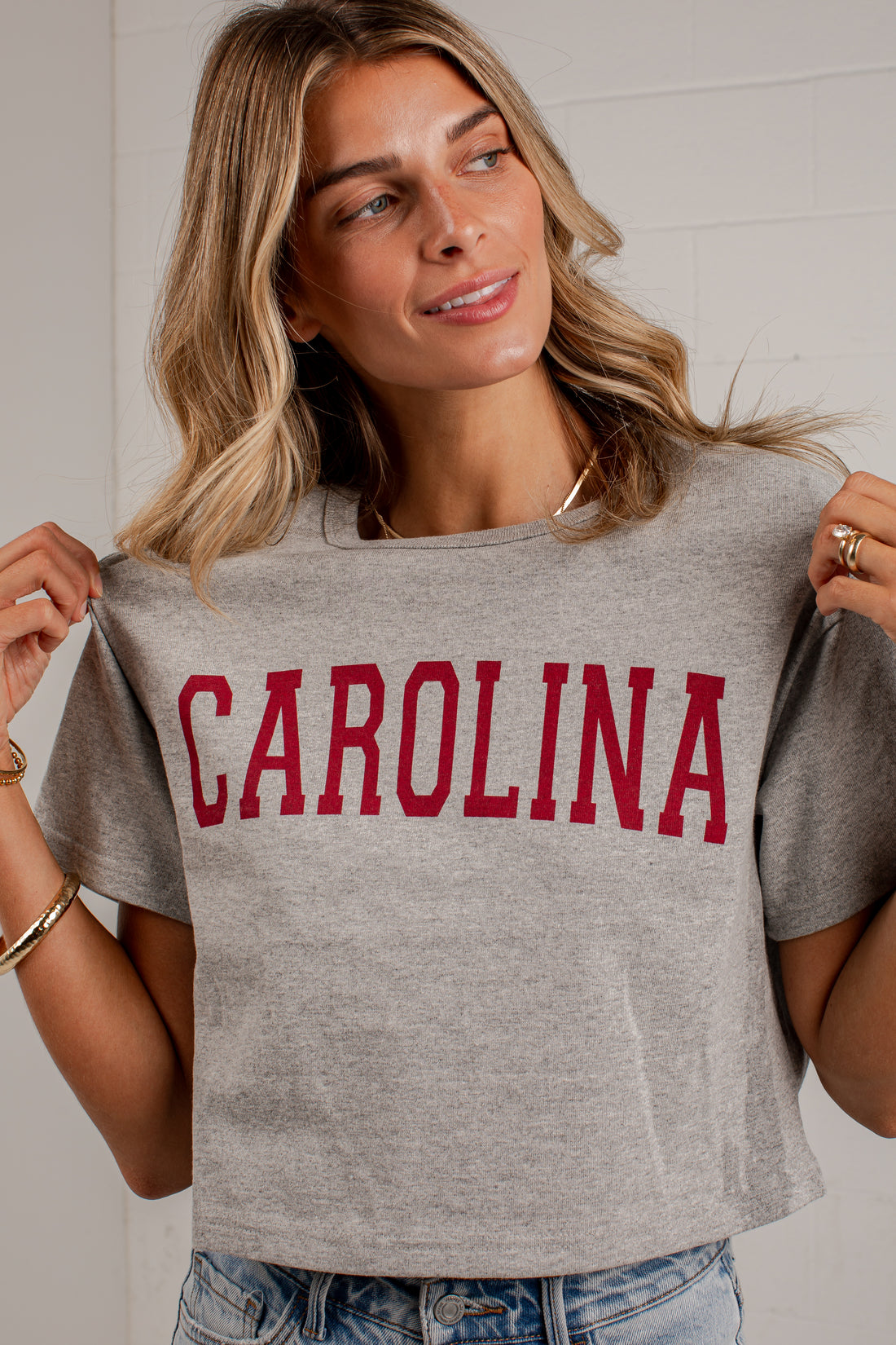 A woman wearing a heather gray cropped t-shirt with &