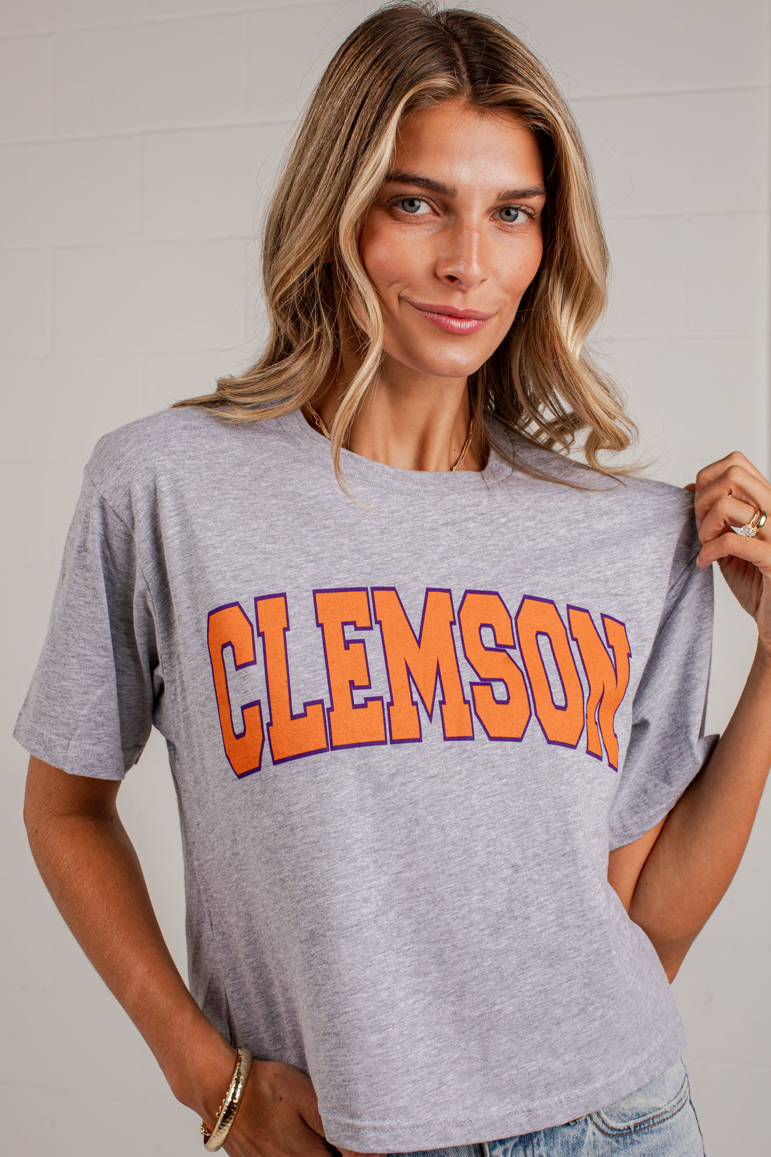 A woman wearing a heather gray Clemson athletic t-shirt with &