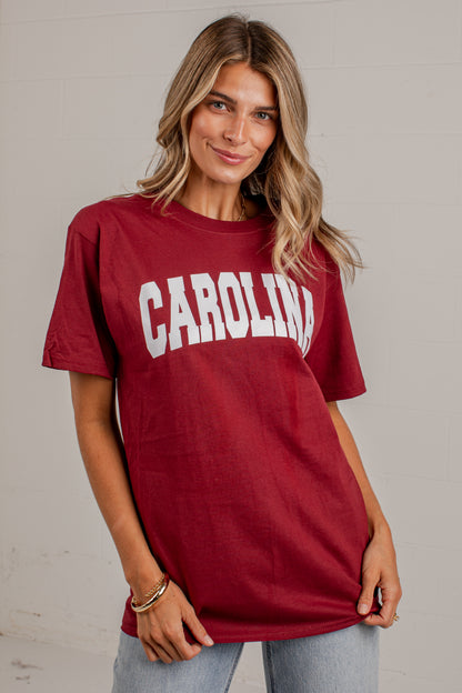 A woman wearing a maroon short-sleeve t-shirt with &