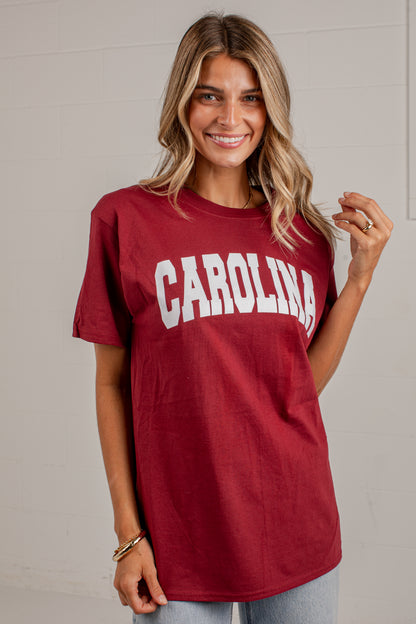 A woman wearing a maroon short-sleeve t-shirt with &