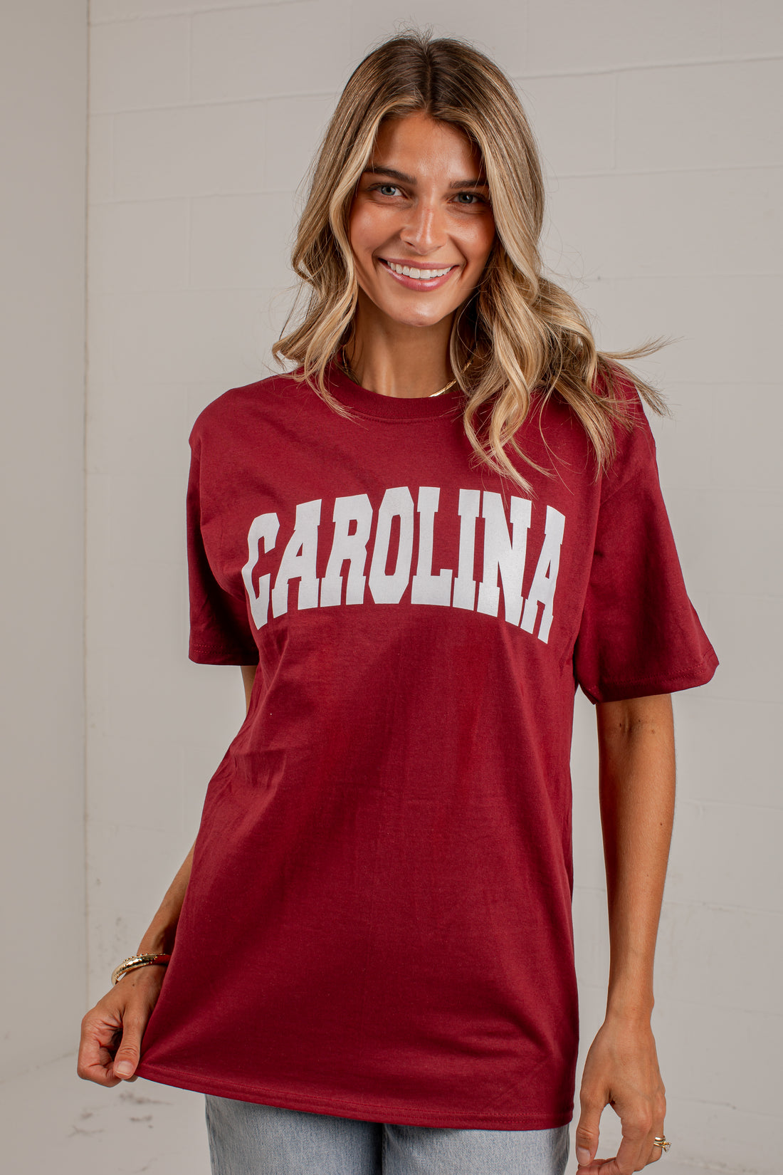 A woman wearing a maroon short-sleeve t-shirt with &
