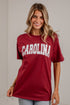 A woman wearing a maroon short-sleeve t-shirt with &