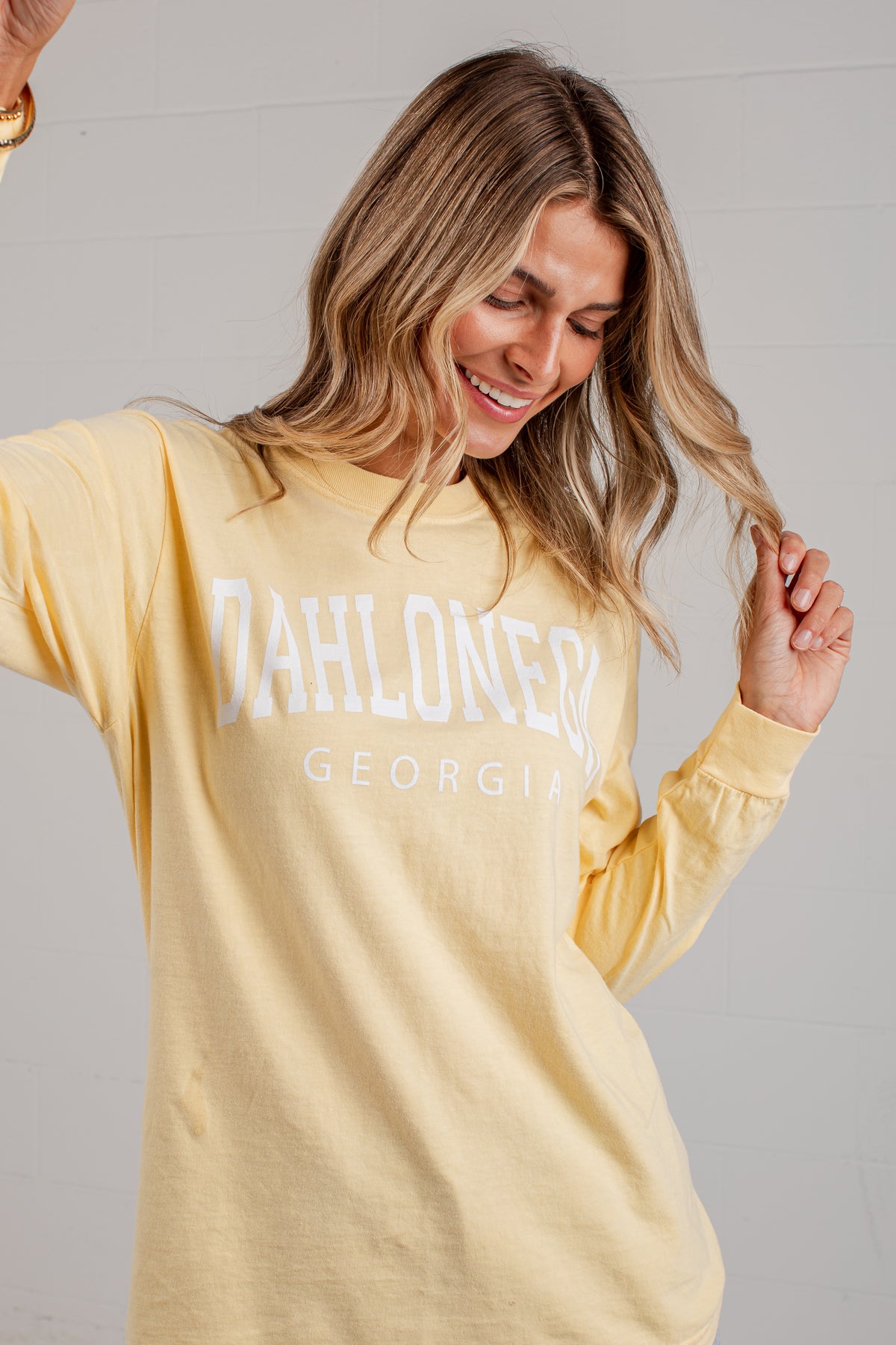 A woman wearing a pale yellow long-sleeve t-shirt with &