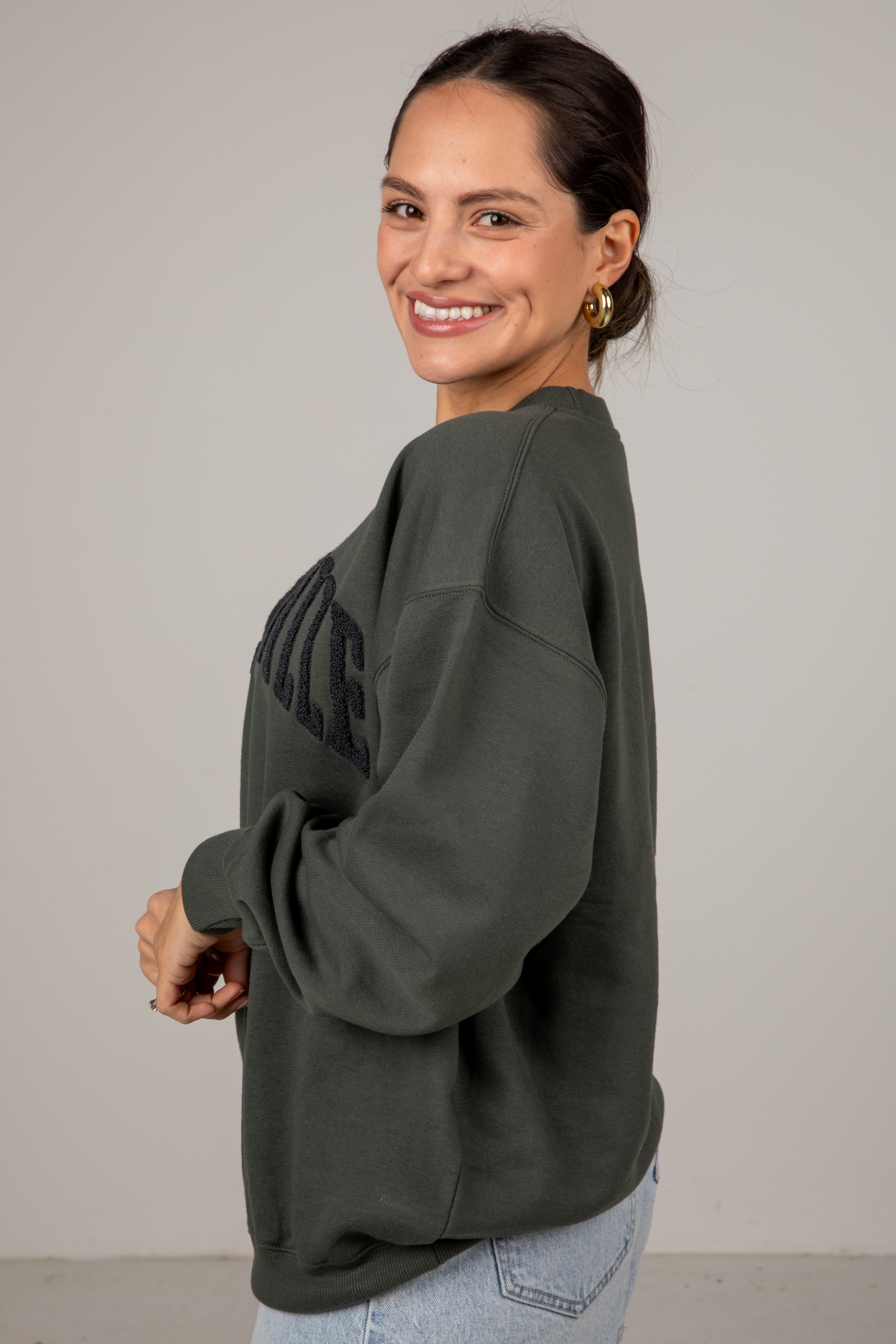 Woman wearing a green sweatshirt with text on the back against a plain background
