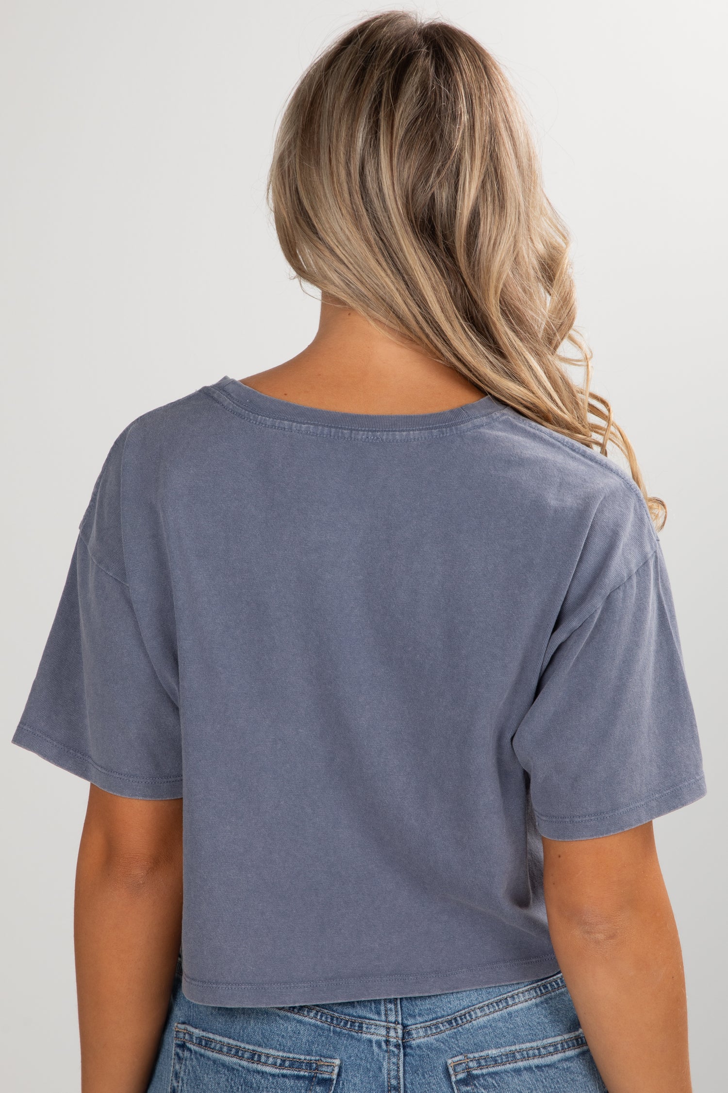 Person wearing a blue t-shirt and jeans on a plain background