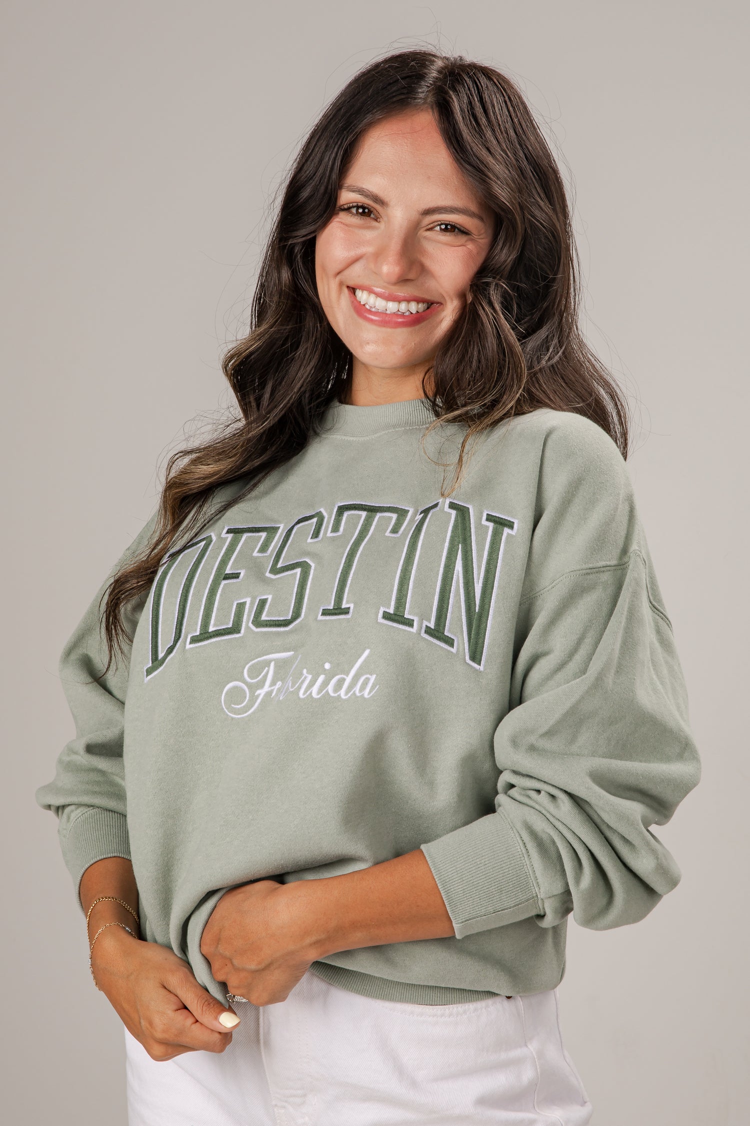 Woman wearing a light green sweatshirt with &