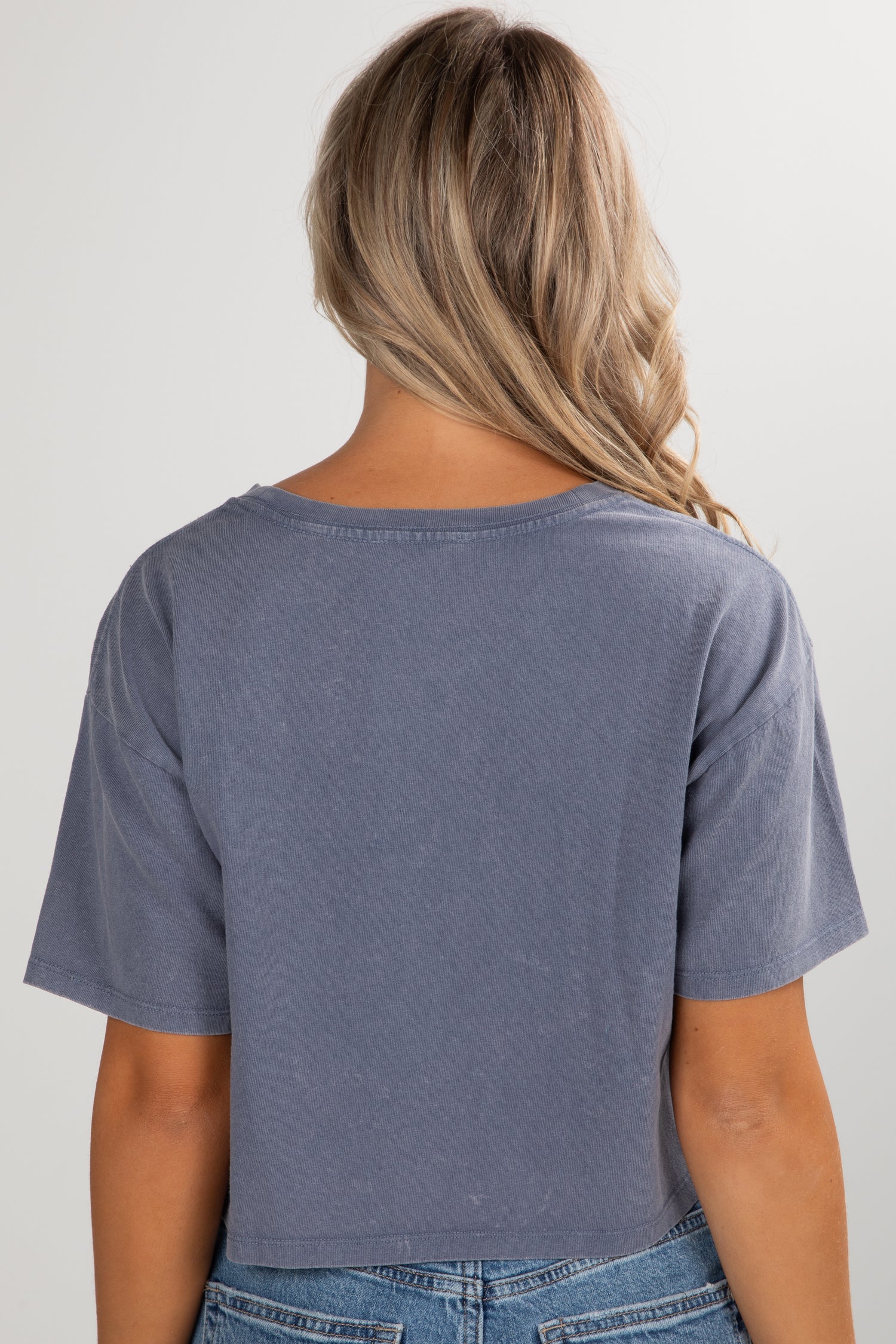 Person wearing a blue t-shirt and jeans on a plain background