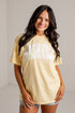 A woman wearing a pale yellow t-shirt with &
