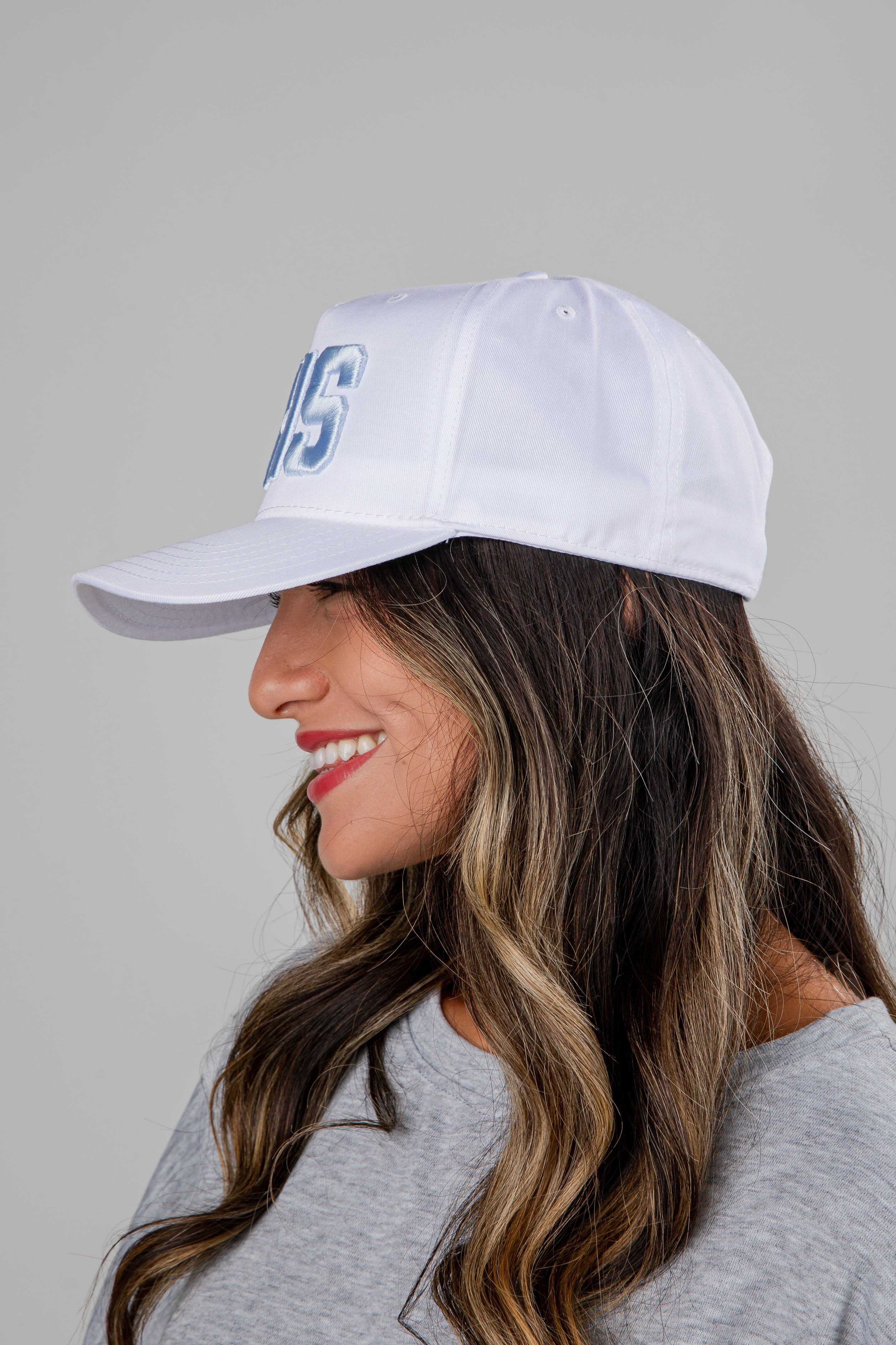 Woman wearing a white cap with blue text on a gray background