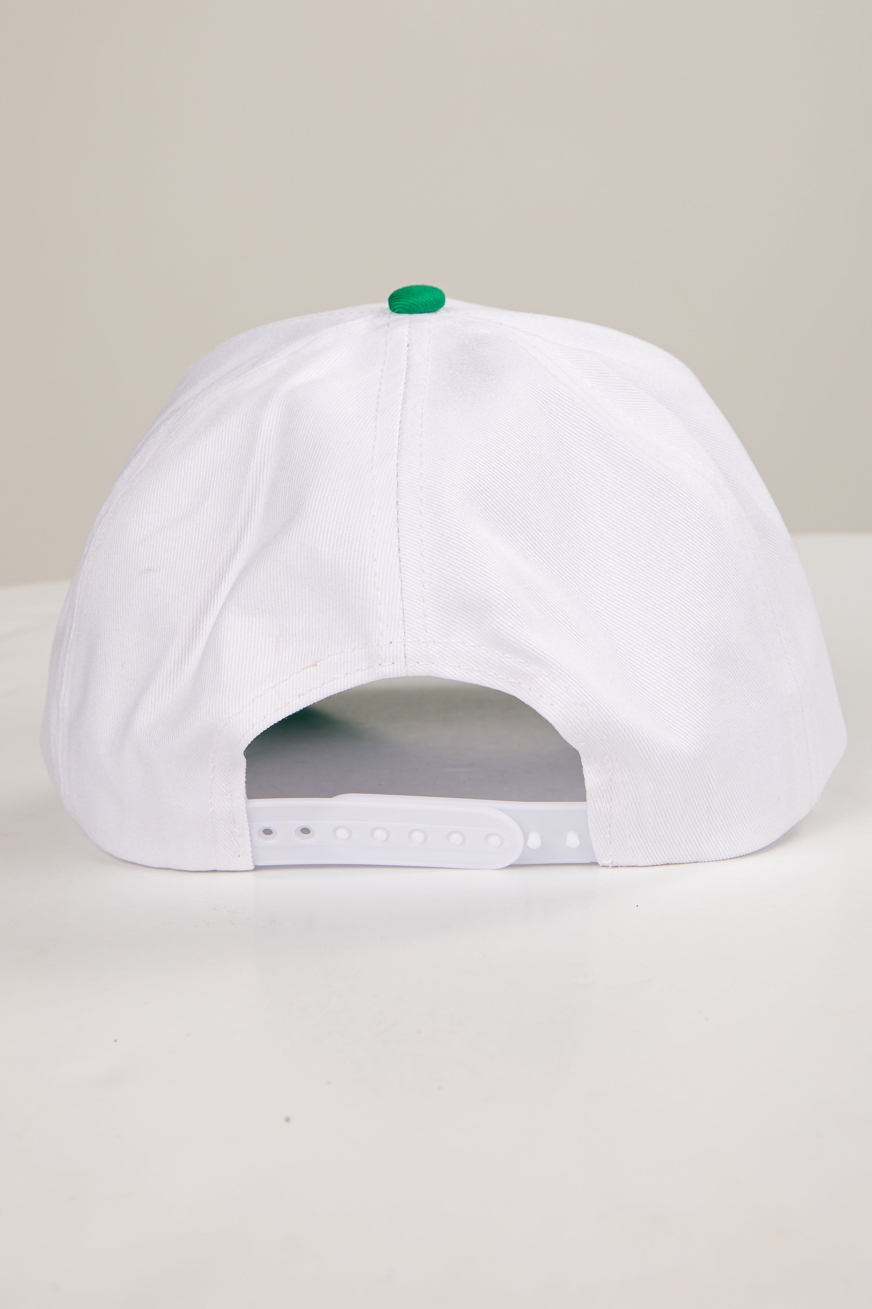 White cap with a green button on a light gray background