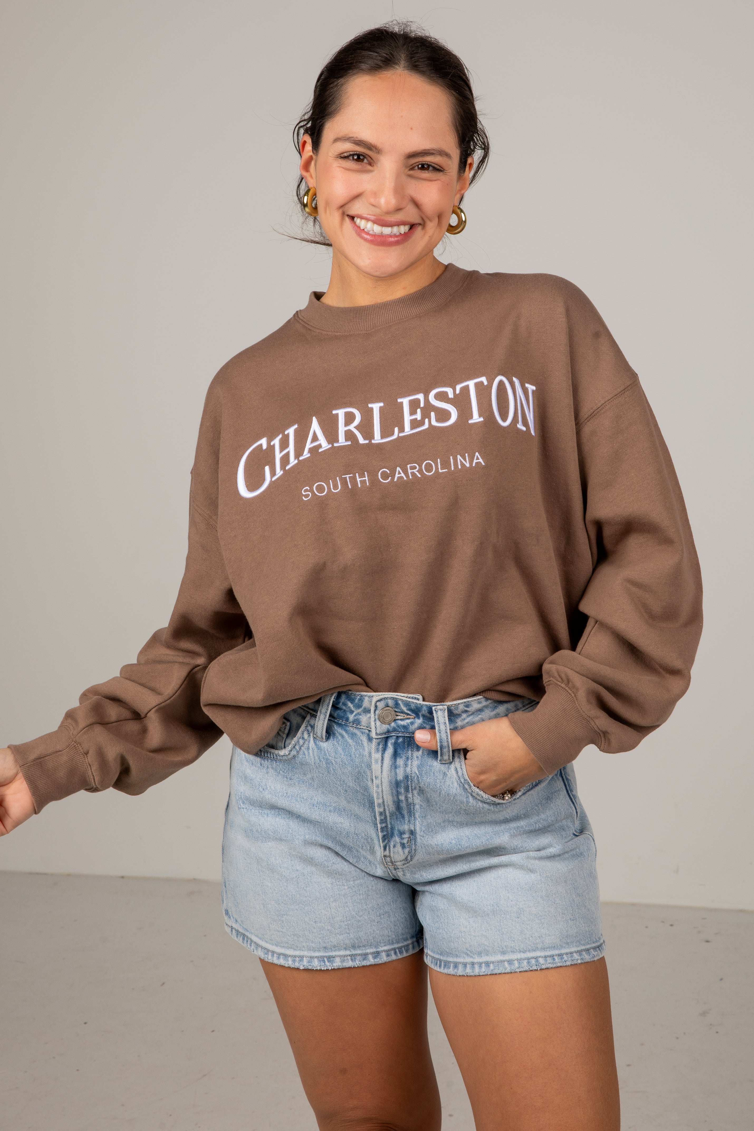 Woman wearing a brown sweatshirt with &