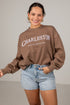 Woman wearing a brown sweatshirt with &