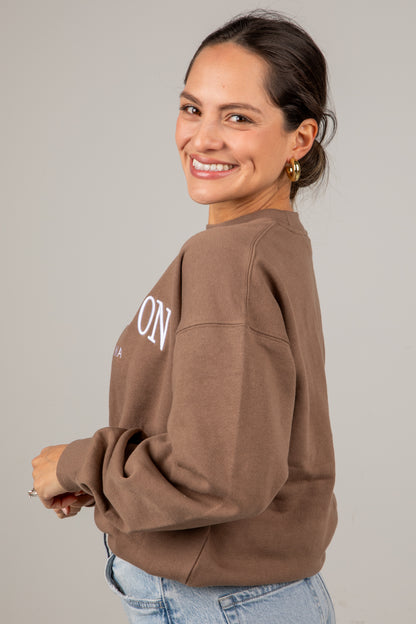 Woman wearing a brown sweatshirt with &