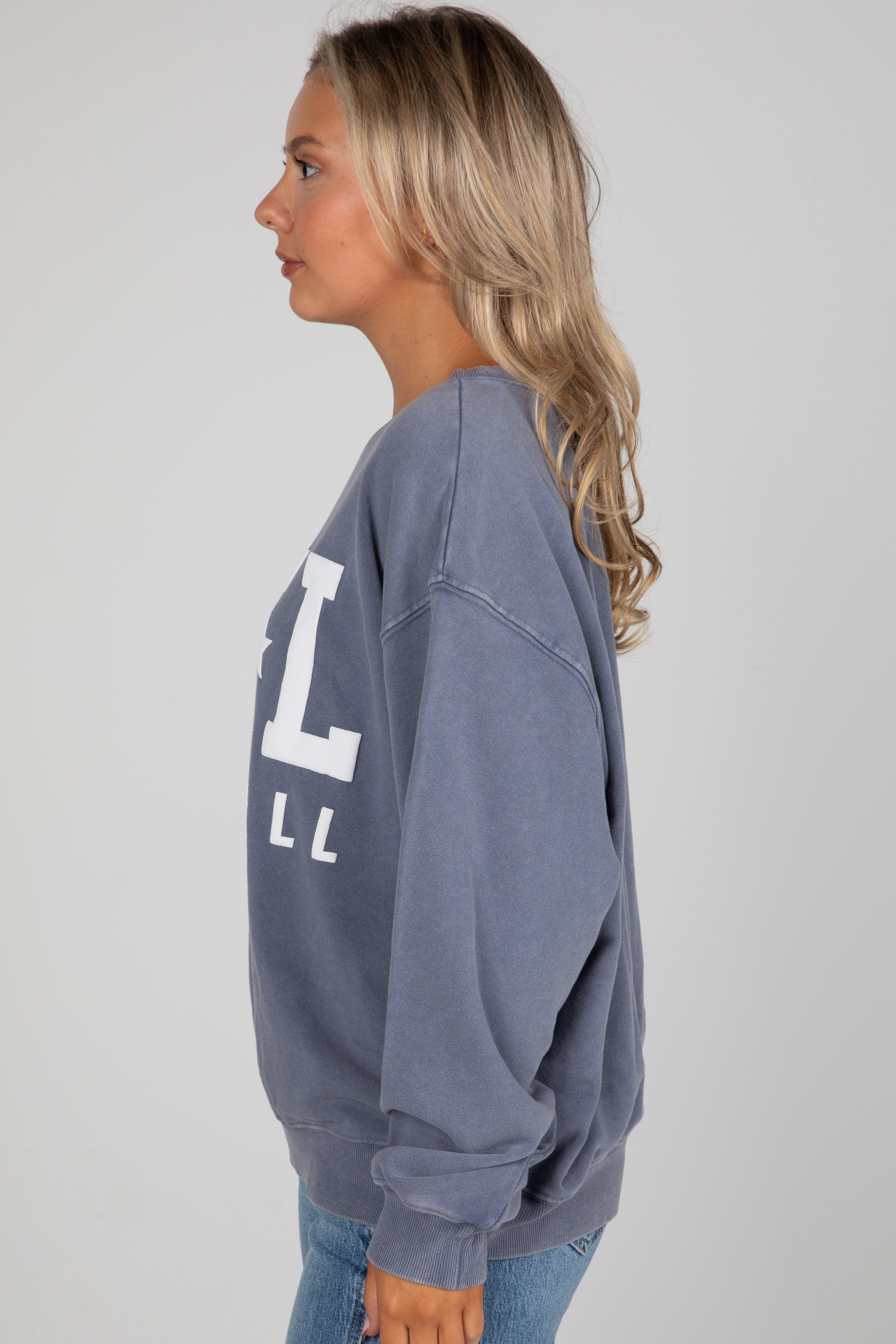 Woman wearing a blue sweatshirt with a large &