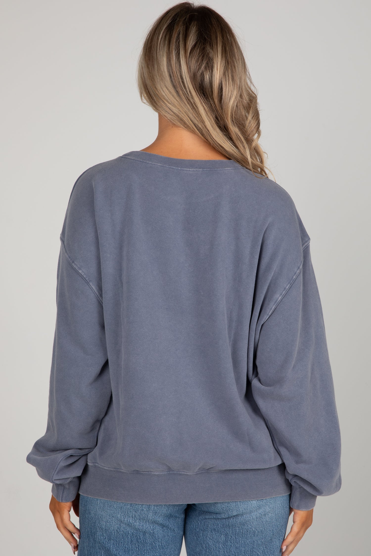 Person wearing a blue sweatshirt and jeans on a plain background