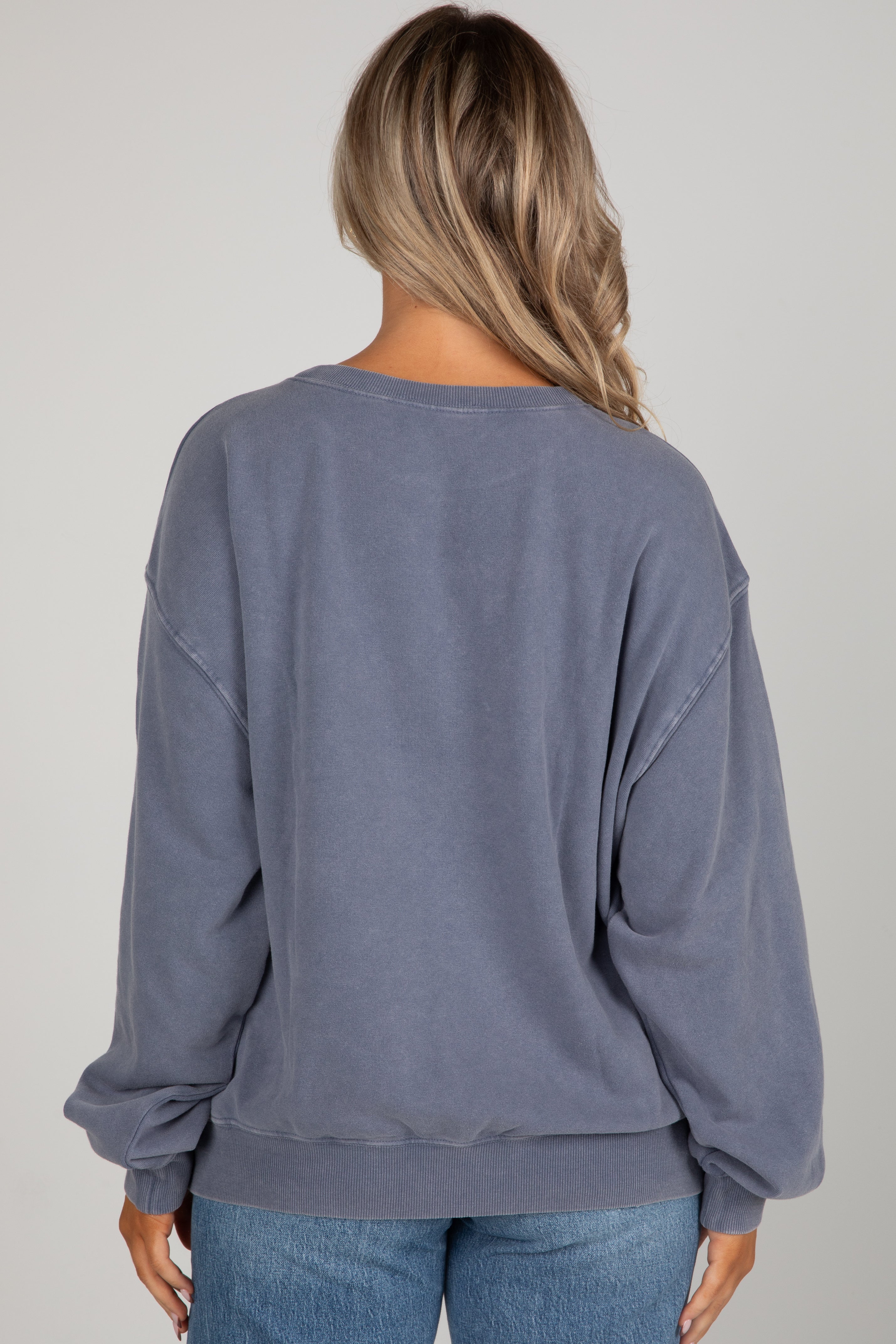 Person wearing a blue sweatshirt and jeans on a plain background