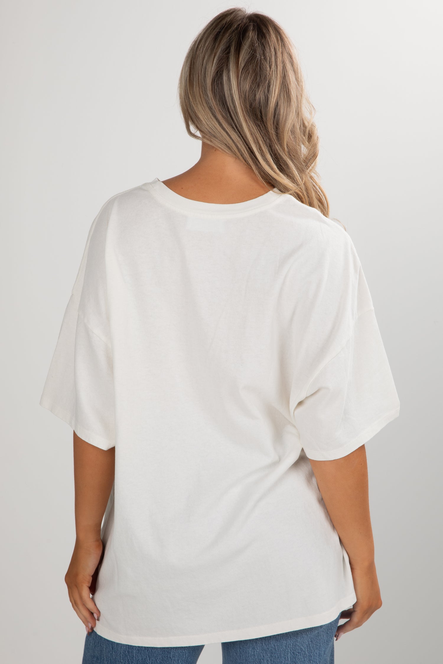 Person wearing a white oversized t-shirt on a plain background