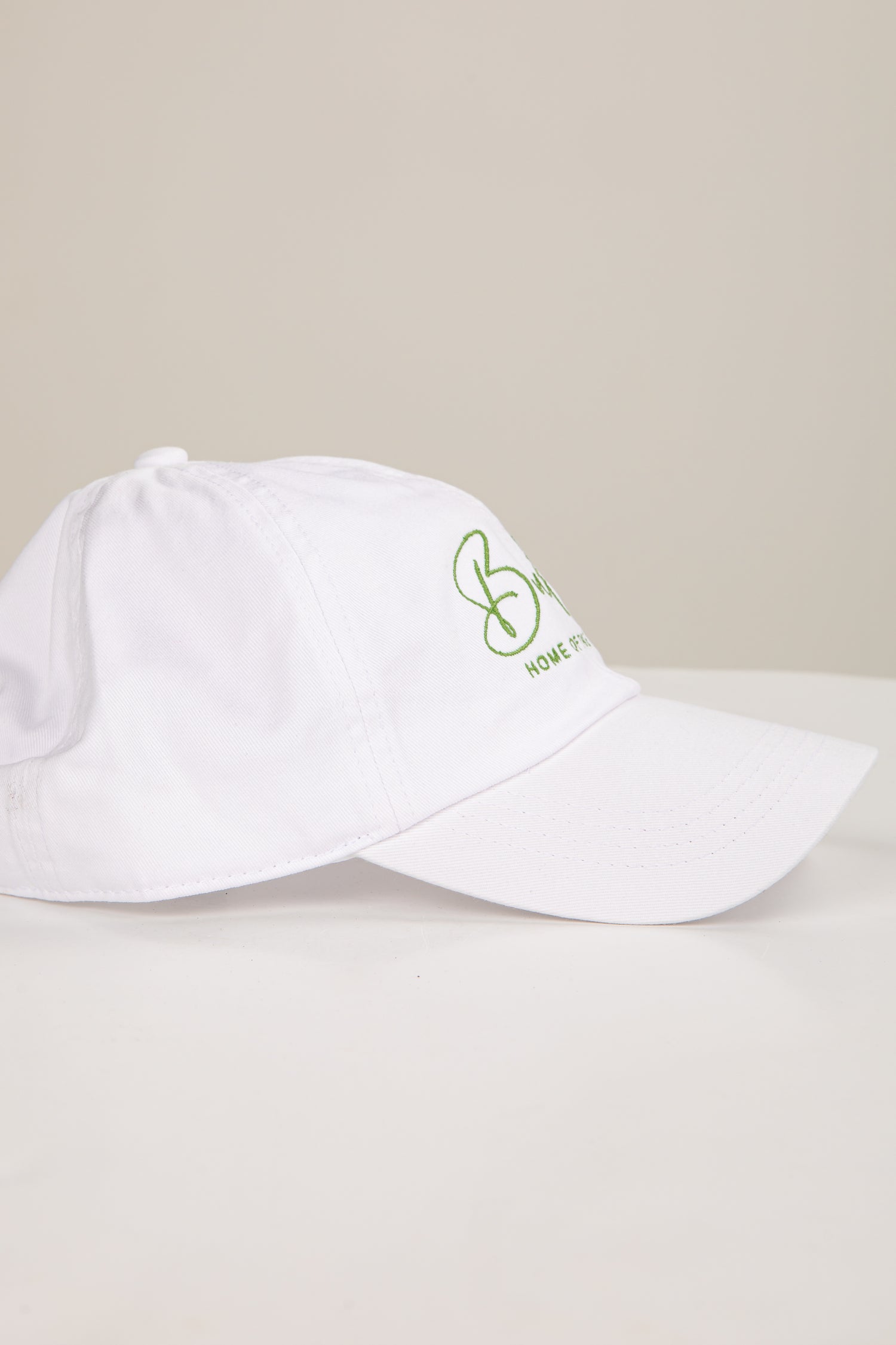White cap with green logo on a light gray background