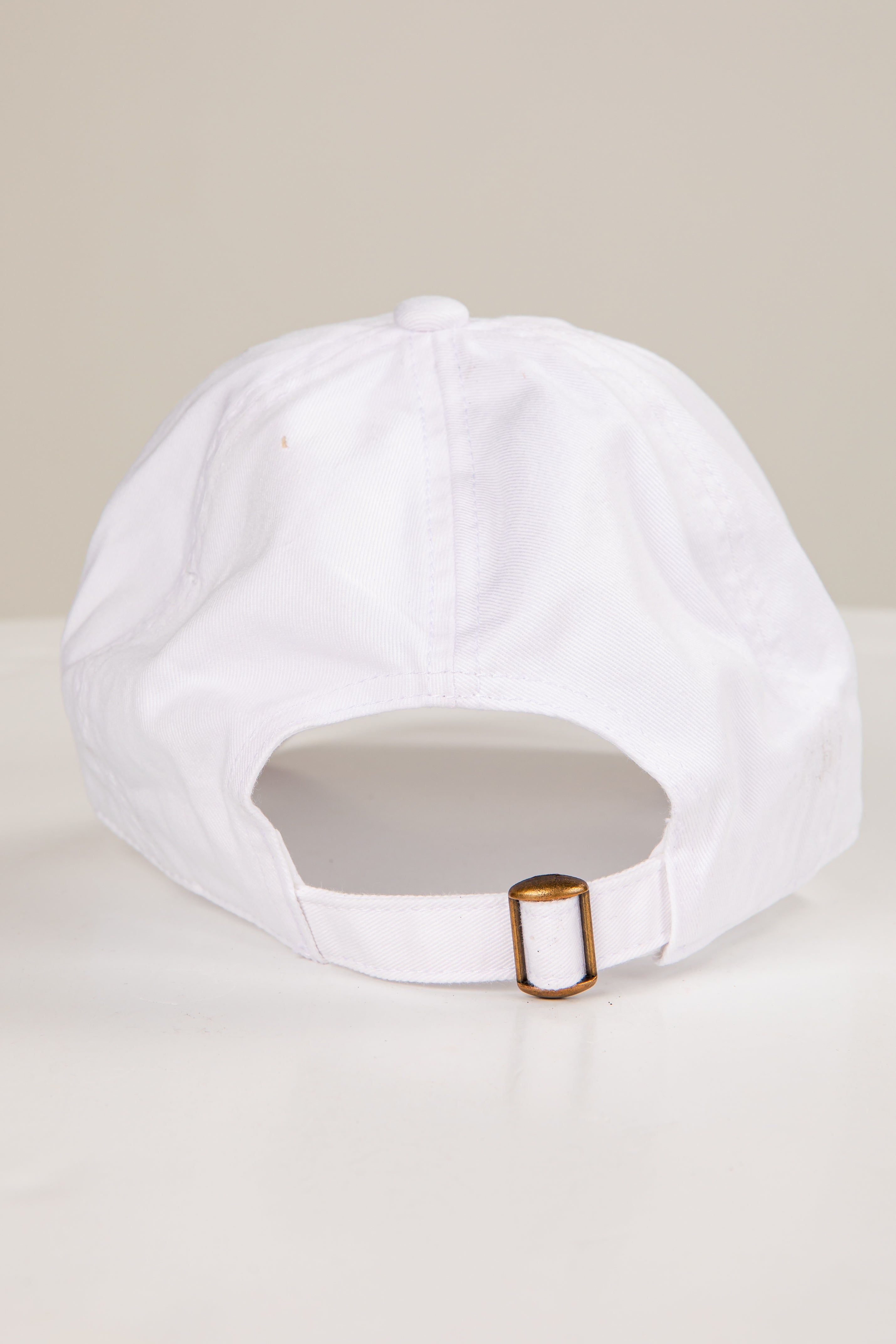 White cap with a gold buckle on a beige background