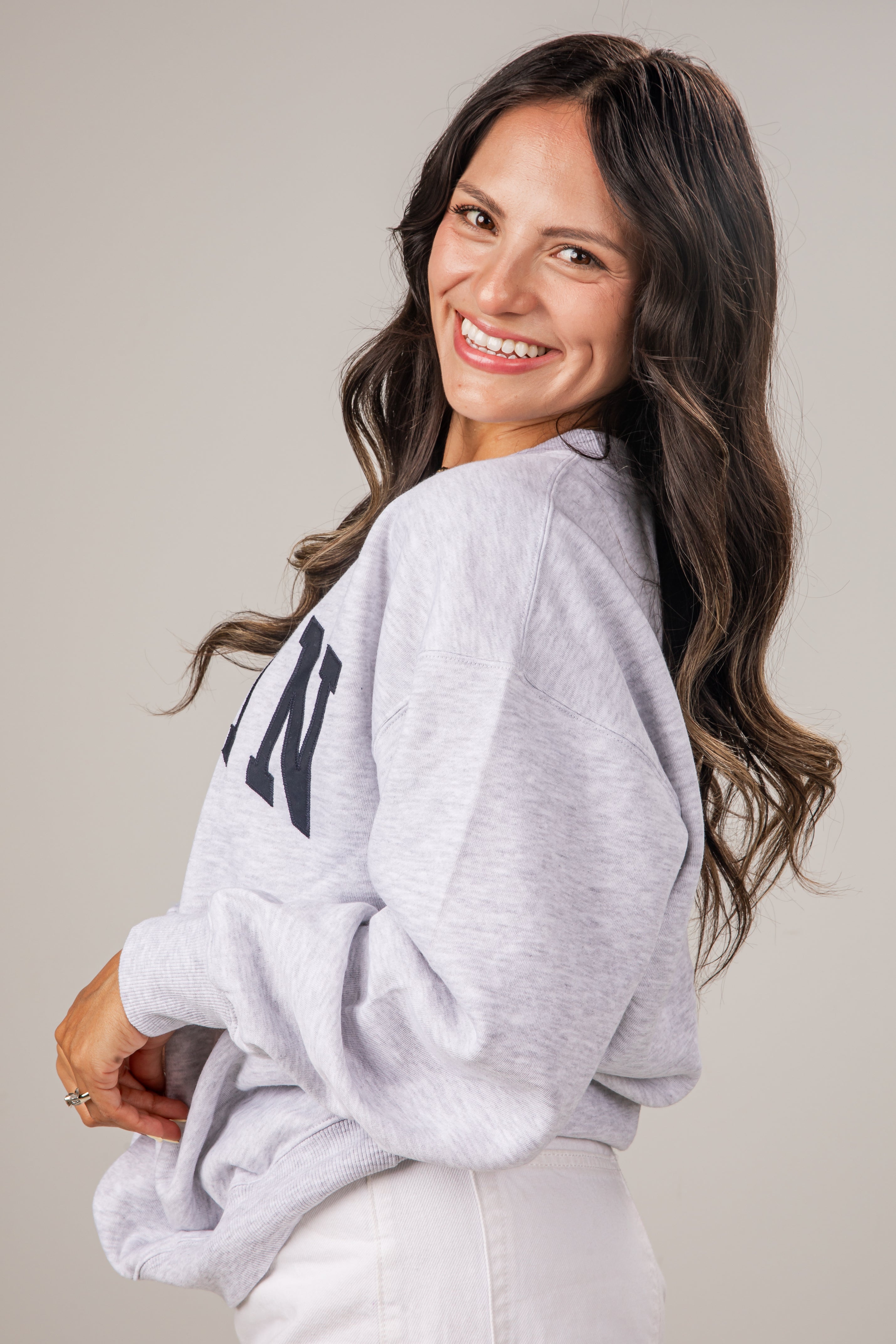 Woman wearing a gray sweatshirt with text on a plain background