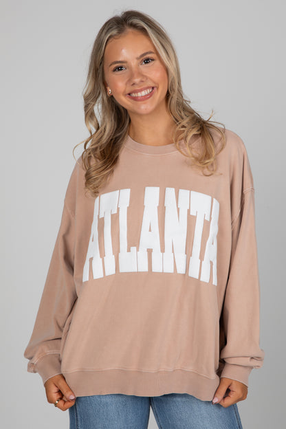 Woman wearing a beige sweatshirt with &