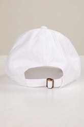 White cap with a gold buckle on a light beige background