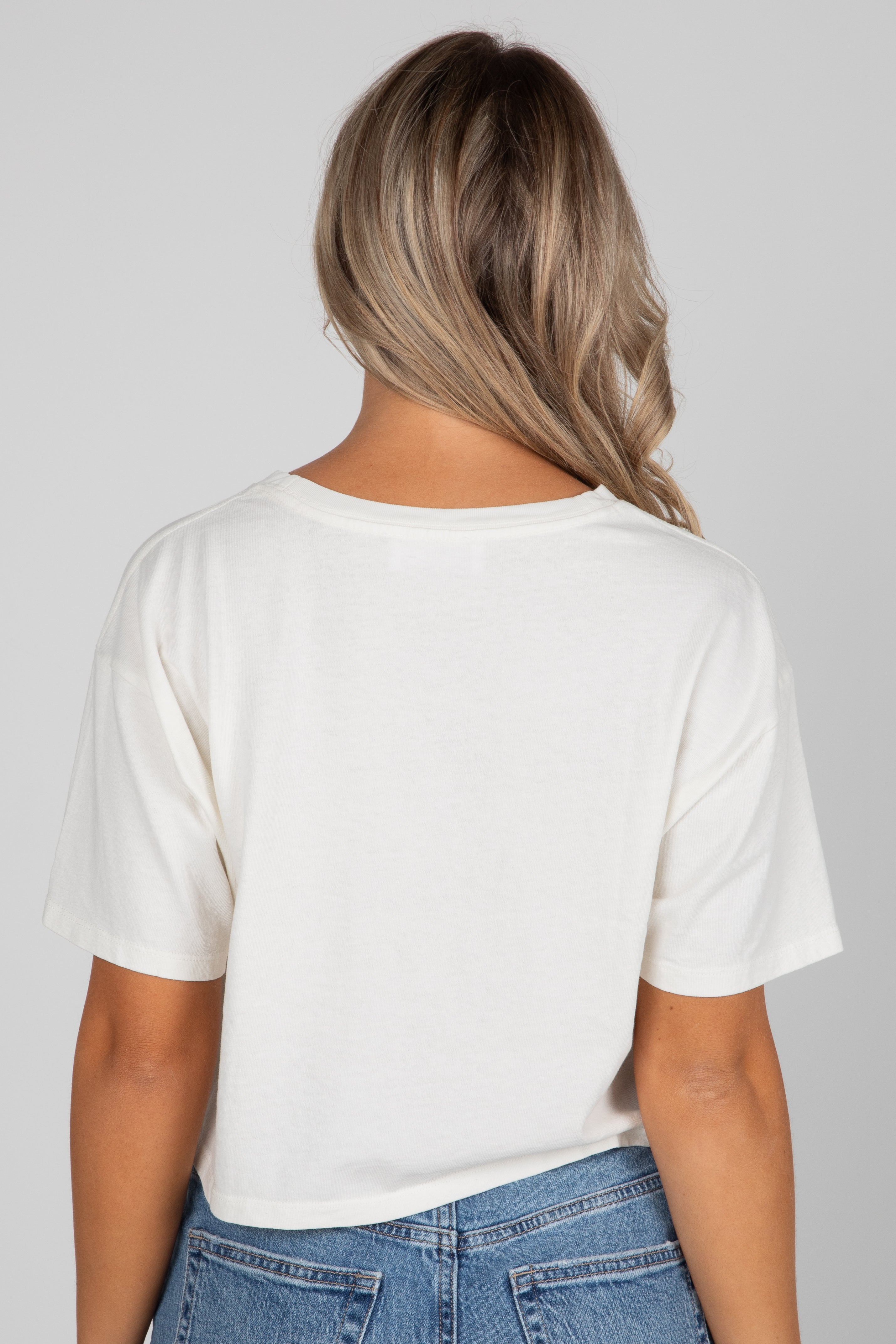 Person wearing a white t-shirt and blue jeans against a plain background