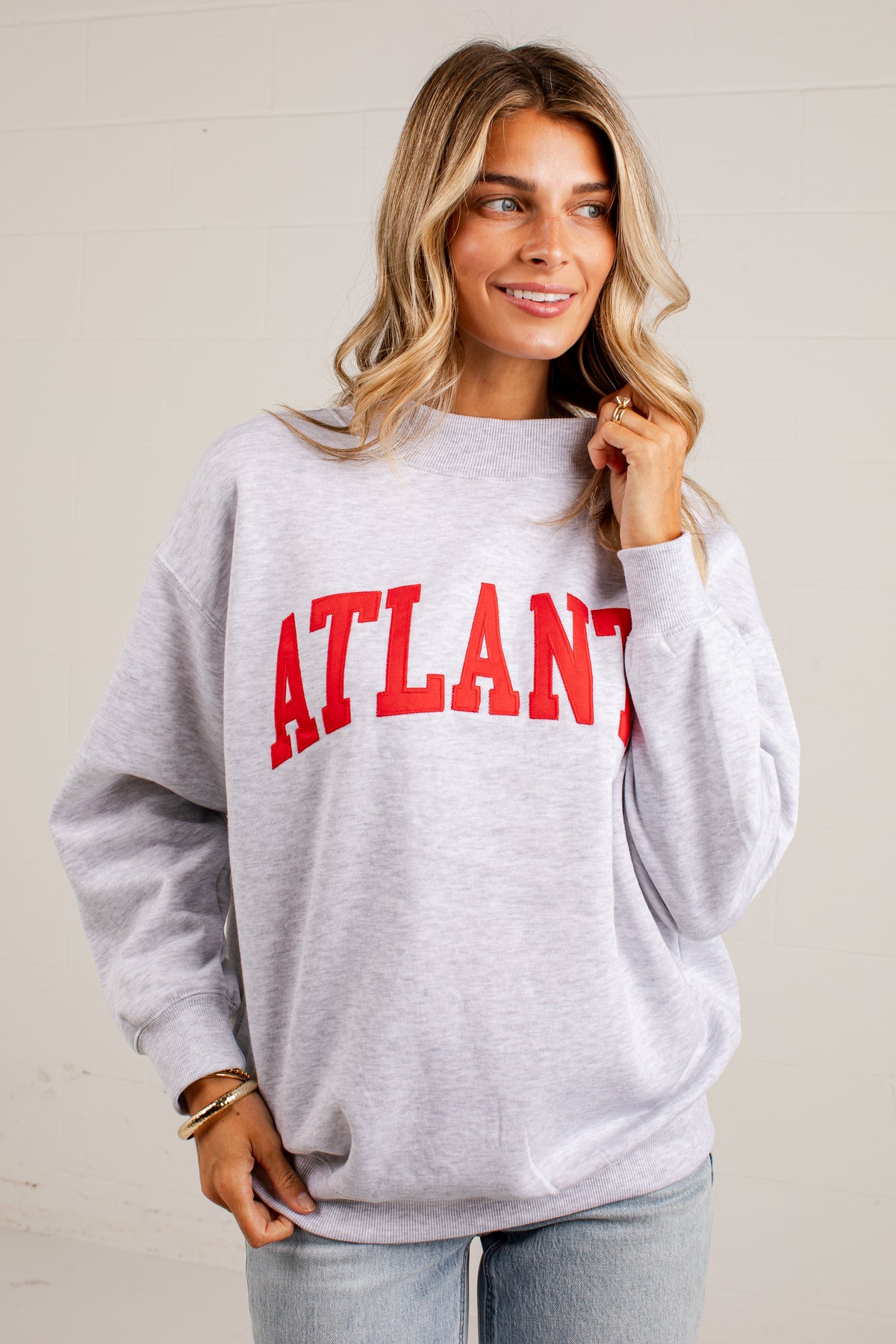 A woman wearing a light heather gray crewneck sweatshirt with &