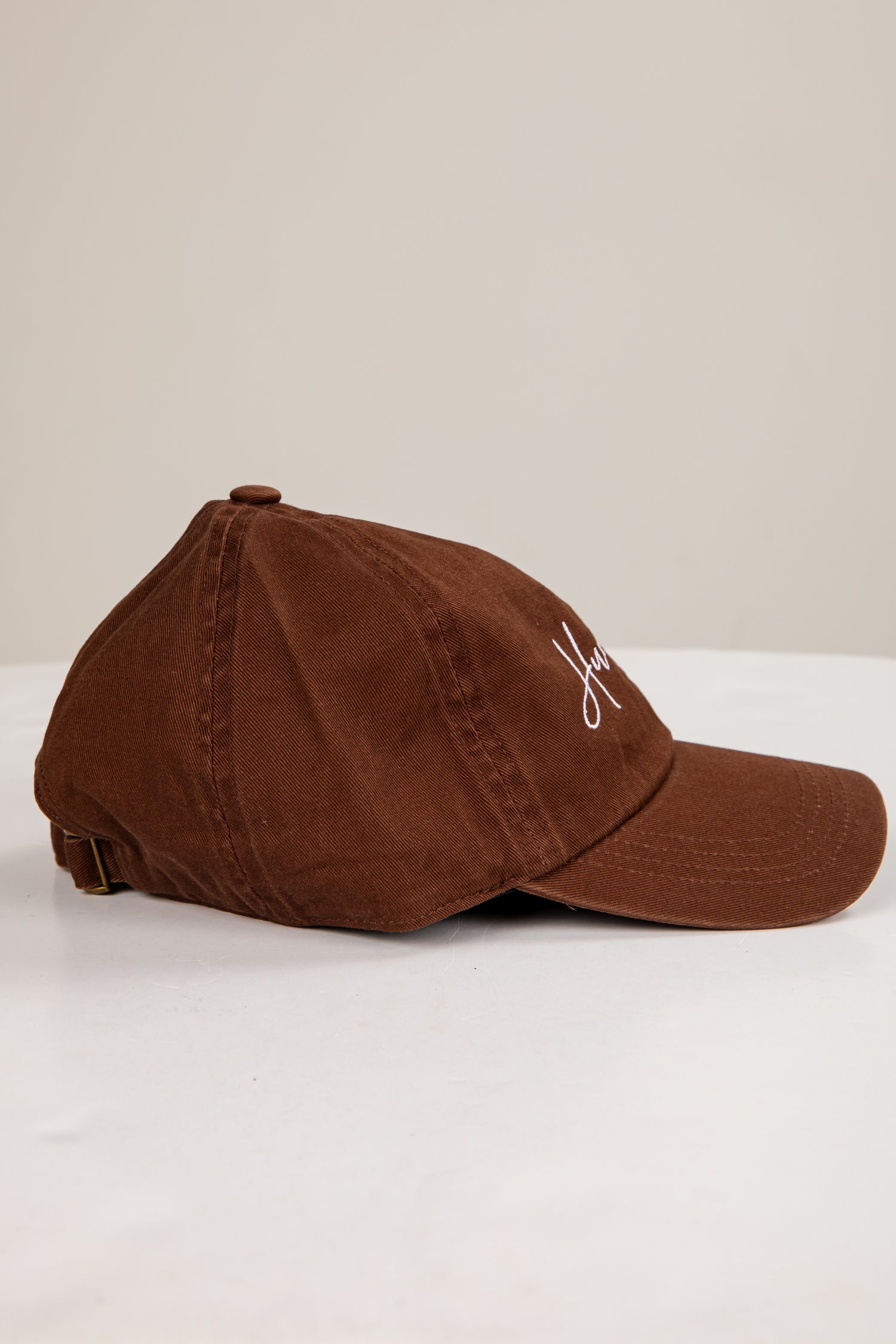 Brown cap with a logo on a white surface and beige background