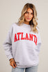 A woman wearing a light heather gray crewneck sweatshirt with &
