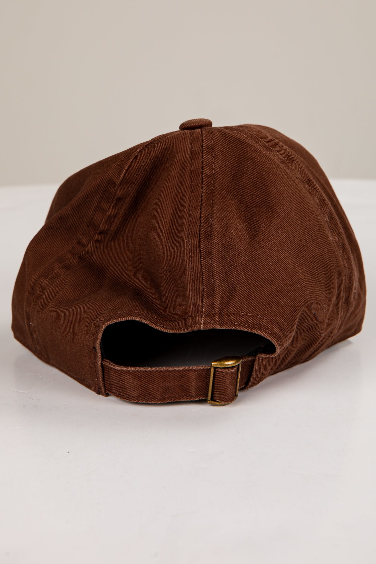 Brown cap with a gold buckle on a white background