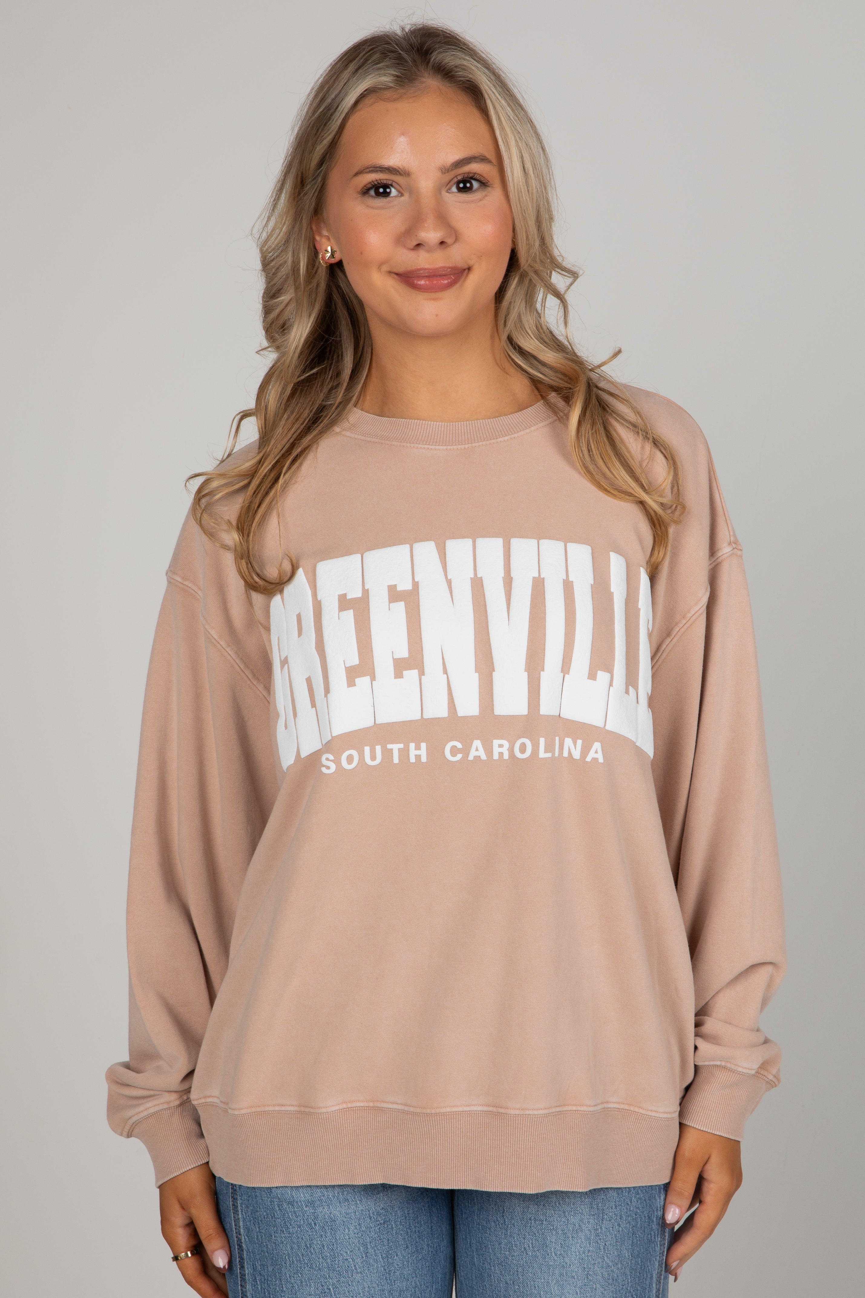 Woman wearing a beige sweatshirt with &