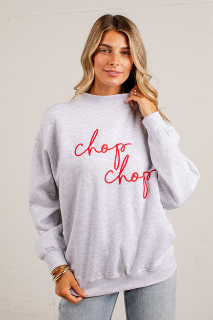 A woman wearing a light heather gray crewneck sweatshirt with &