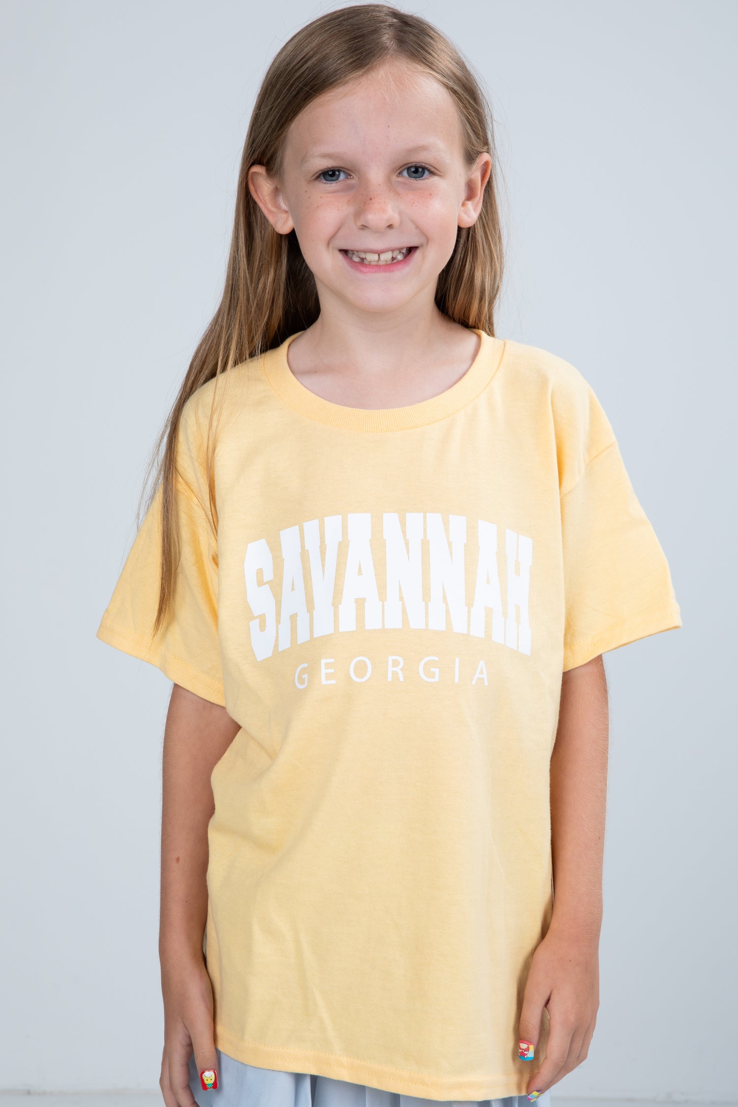 Young girl wearing a yellow t-shirt with &