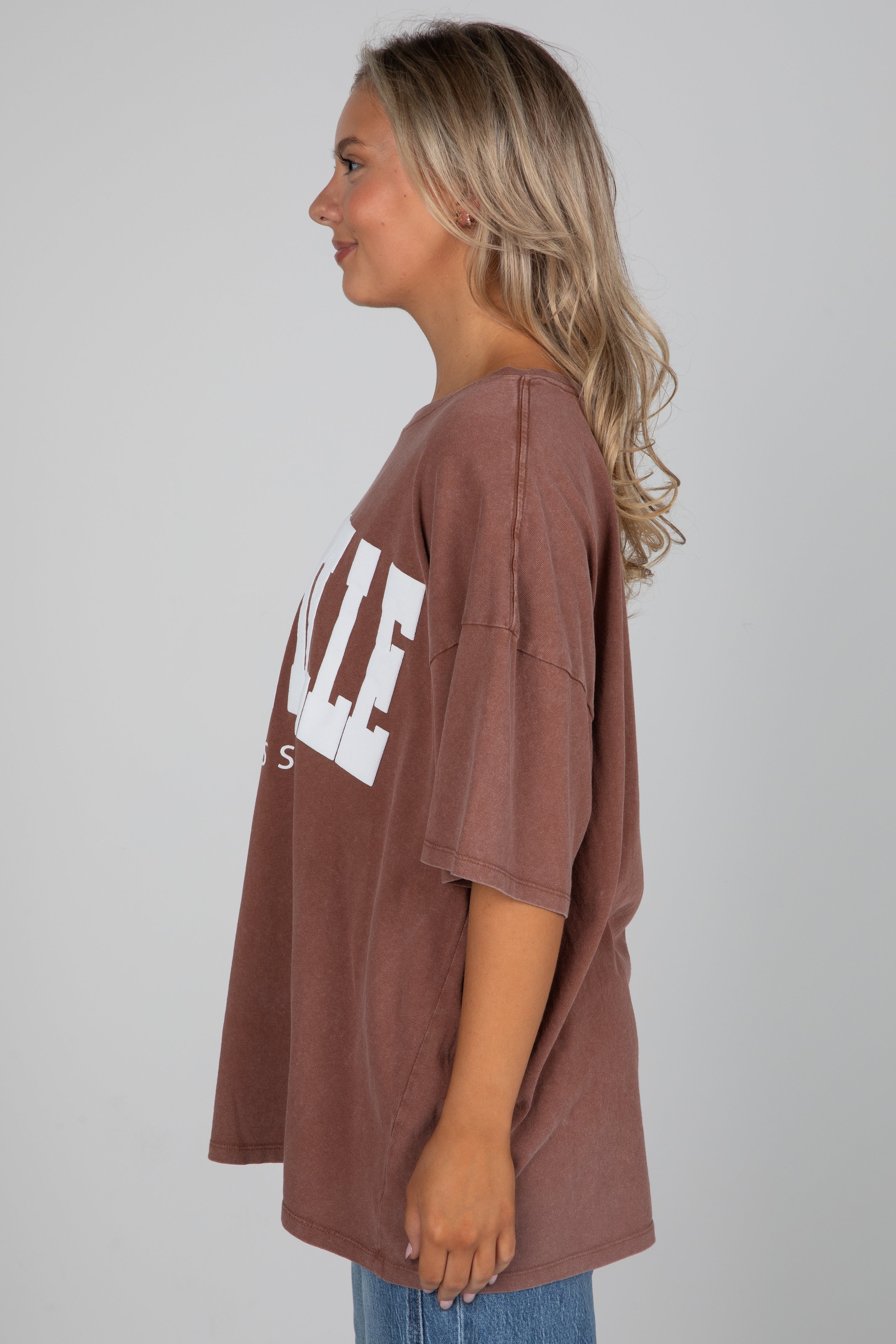 Woman wearing a brown oversized t-shirt with &