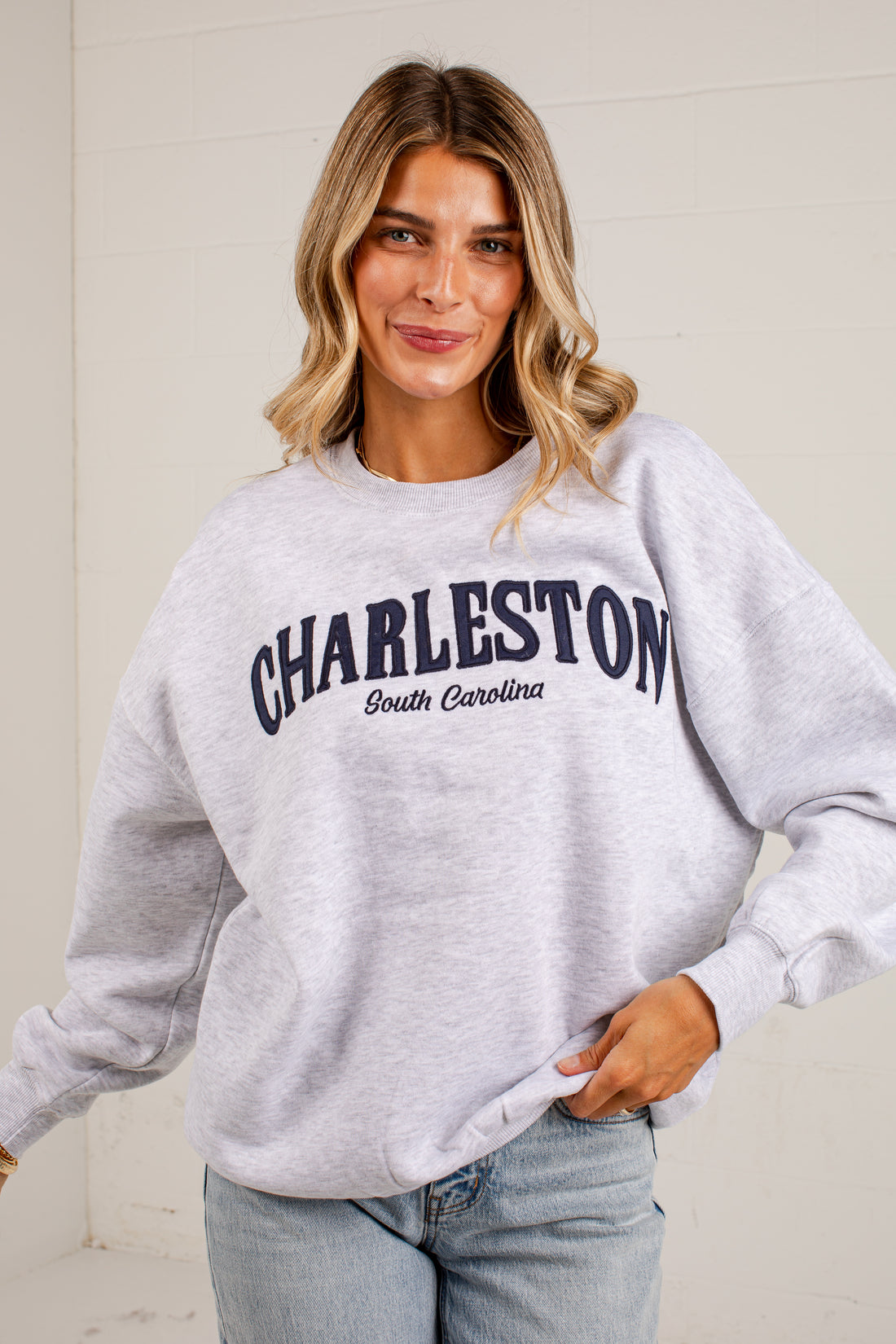 A woman wearing a light heather gray sweatshirt with &